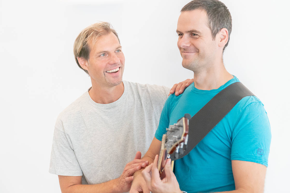 Andreas unterrichtet Gitarristen mit sanften Berührungen an Schulter und Arm